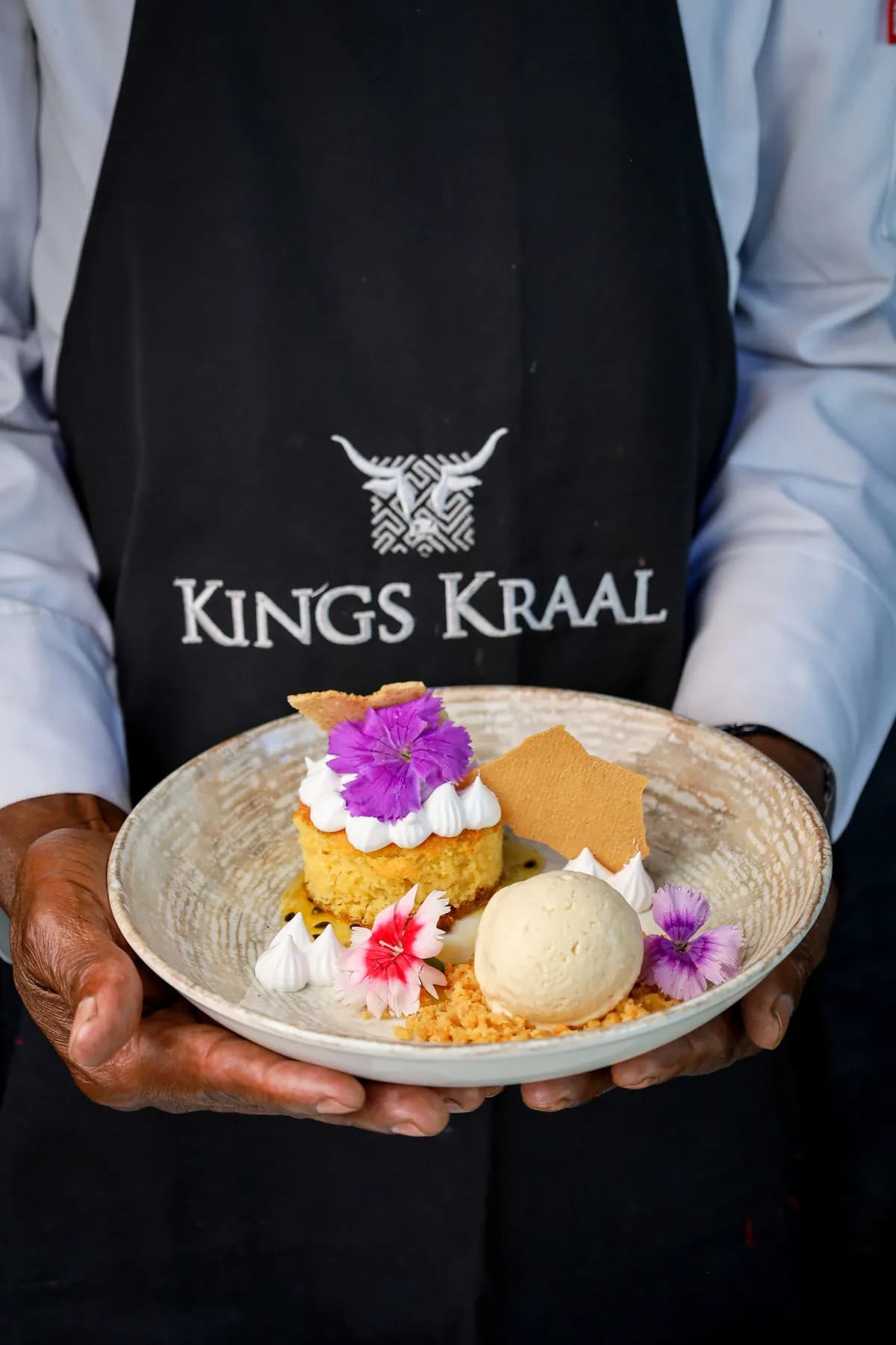 Plated dessert with ice cream, edible flowers and crisp biscuits presented by a King’s Kraal chef.