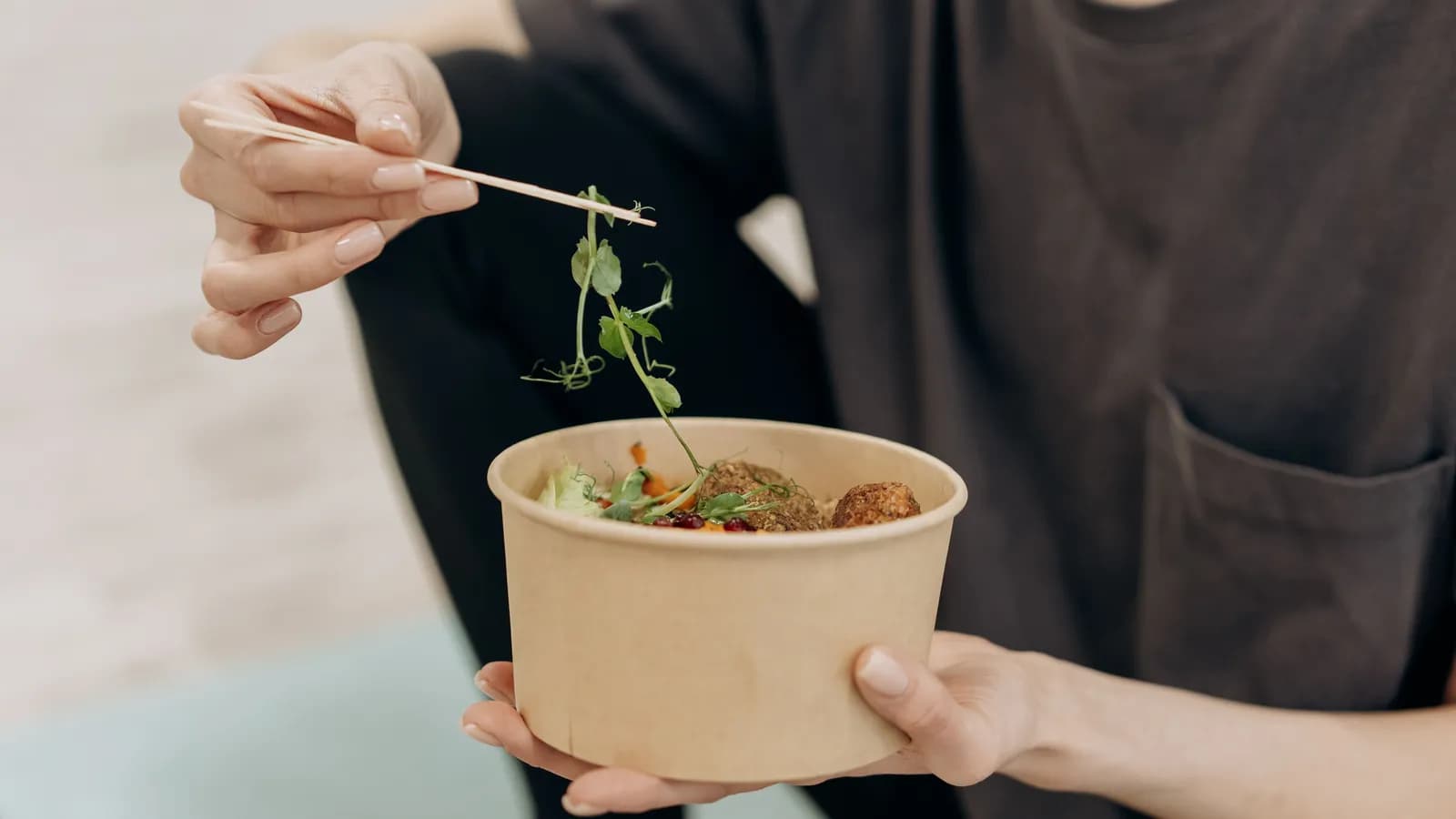 Woman sitting down and eating a salad