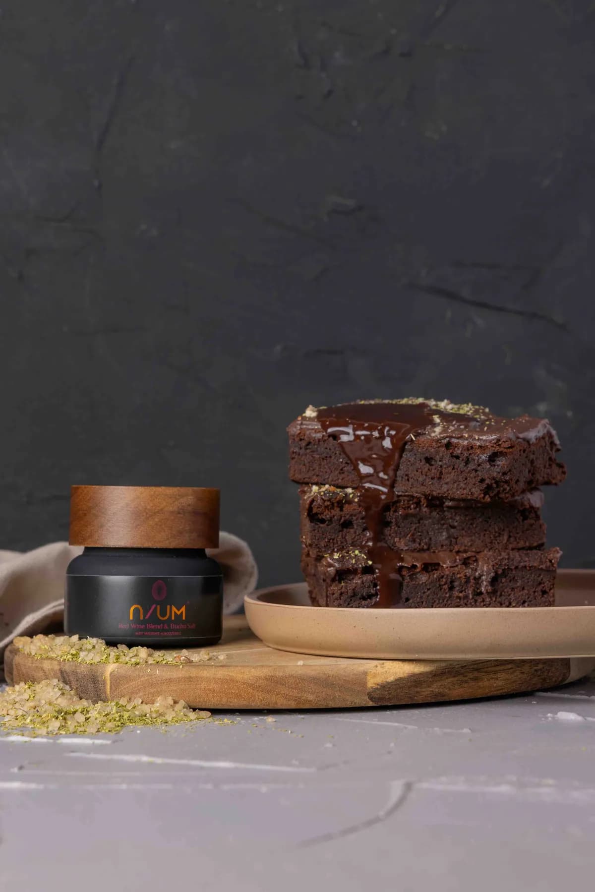 Stack of chocolate brownies with chocolate sauce styled alongside N/UM Shiraz and hibiscus salt.